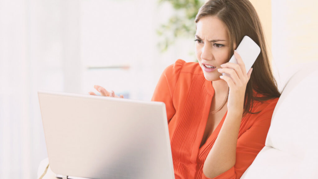A woman talking on the phone reviewing things on a computer