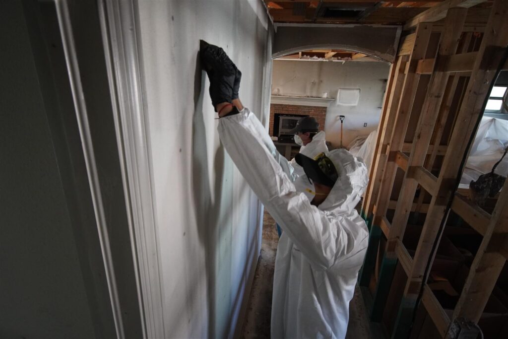 Workers cleaning a wall of soot after a fire