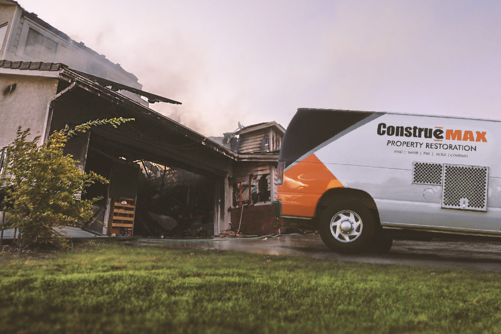 House damaged from a fire with an emergency services truck in the driveway